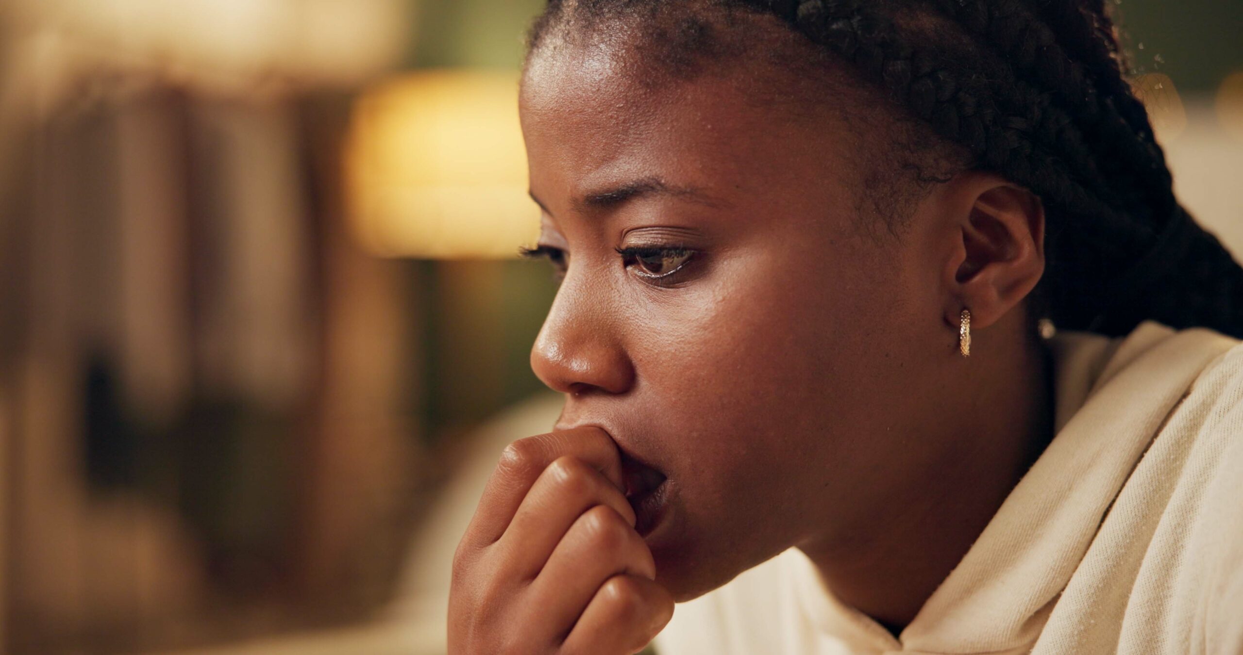 A thoughtful young woman sits in quiet contemplation, symbolizing the internal struggle between fear and intuition.
