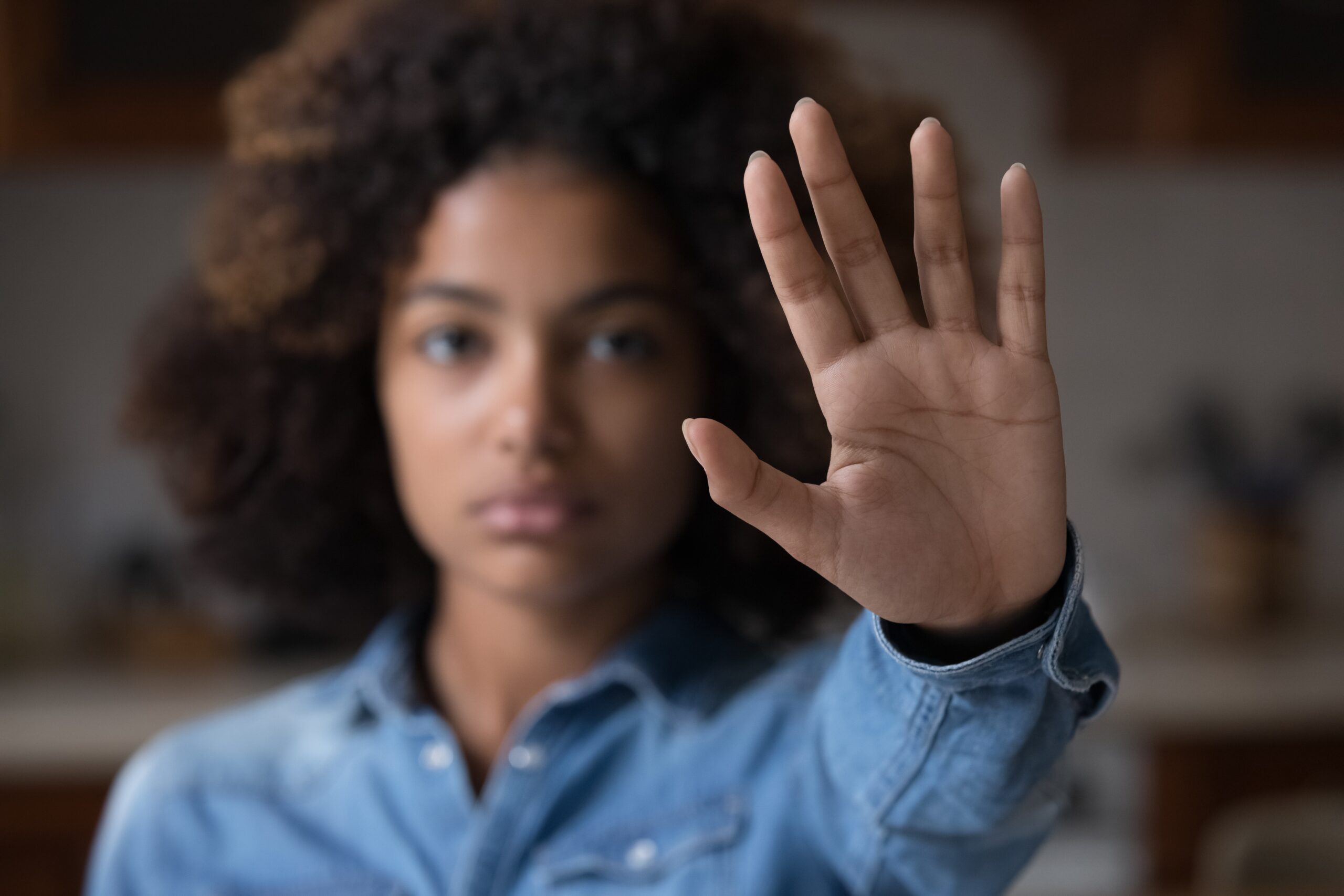 A young woman holding up her hand in a stopping gesture, symbolizing rejection and personal boundaries.